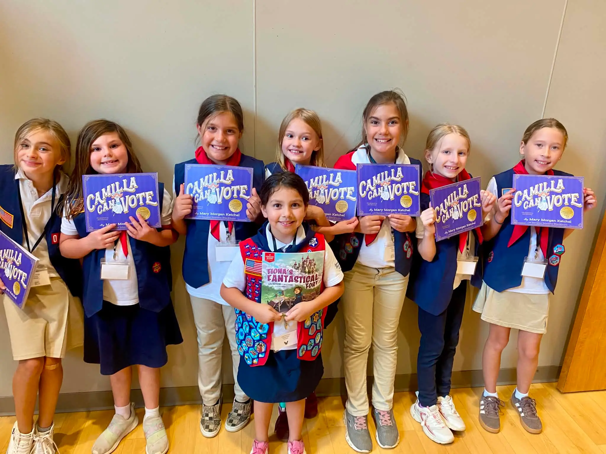 An American Heritage Girls troop lined up holding their donated copies of Camilla Can Vote and Fiona's Fantastical Fort